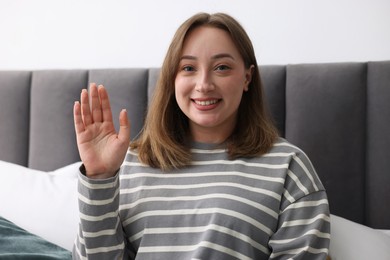 Photo of Portrait of happy woman waving at home. Online medical consultation