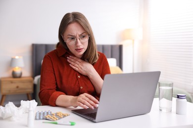 Photo of Woman having online consultation with doctor via laptop at table indoors