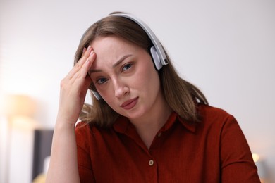 Photo of Woman in headphones having online consultation with doctor at home