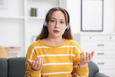 Photo of Woman in headphones having online consultation with doctor at home