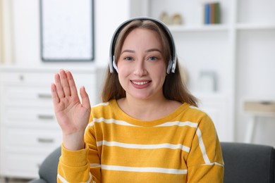 Photo of Woman in headphones having online consultation with doctor at home