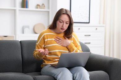 Photo of Sick woman having online consultation with doctor via laptop on sofa at home