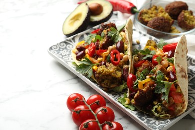 Photo of Tasty vegetarian tacos with falafel and other ingredients on white marble table, closeup. Space for text