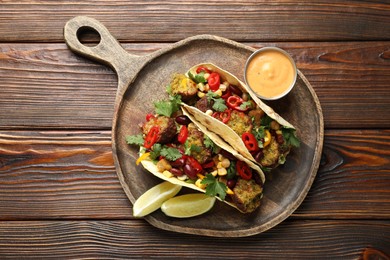 Photo of Tasty vegetarian tacos with falafel served with sauce on wooden table, top view