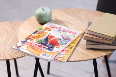 Photo of Lifestyle magazines and books on wooden nesting tables indoors, closeup