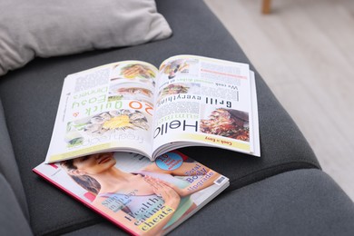 Photo of Lifestyle magazines on sofa indoors, closeup view