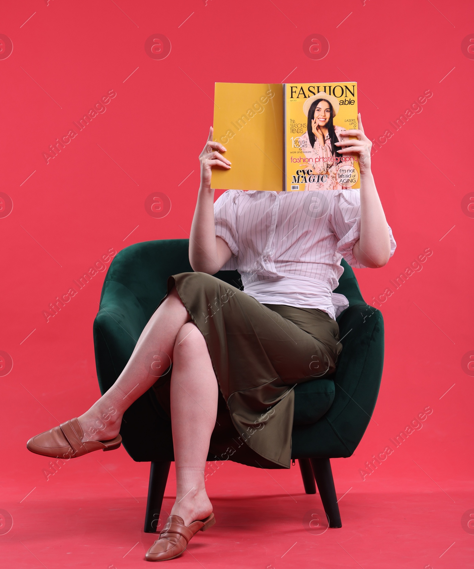 Woman with fashion magazine on armchair against red background Photo of Woman with fashion magazine on armchair against red background