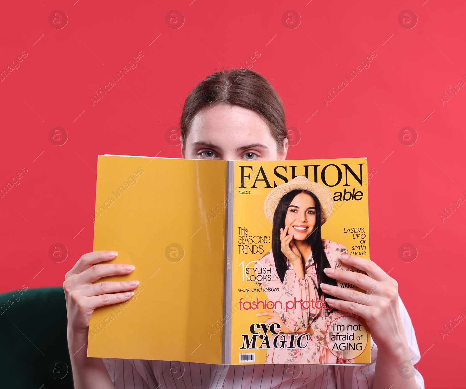 Woman with fashion magazine on armchair against red background Photo of Woman with fashion magazine on armchair against red background
