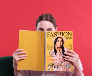 Photo of Woman with fashion magazine on armchair against red background