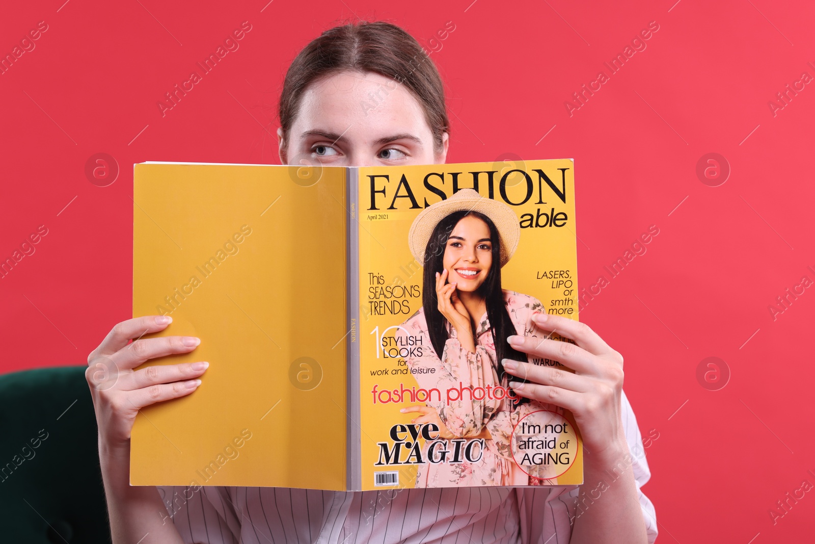 Woman with fashion magazine on armchair against red background Photo of Woman with fashion magazine on armchair against red background