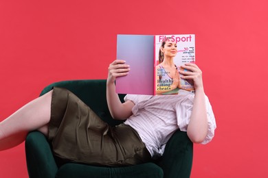 Photo of Woman with lifestyle magazine on armchair against red background