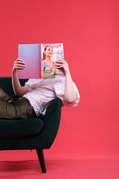 Photo of Woman with lifestyle magazine on armchair against red background