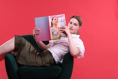 Photo of Woman with lifestyle magazine on armchair against red background, space for text