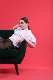 Photo of Beautiful young woman sitting on armchair against red background