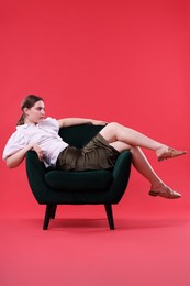 Photo of Beautiful young woman sitting on armchair against red background