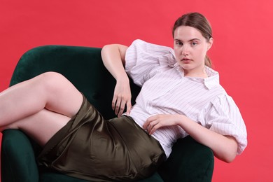 Photo of Beautiful young woman sitting on armchair against red background