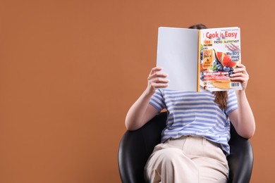 Photo of Woman with lifestyle magazine on armchair against brown background, space for text