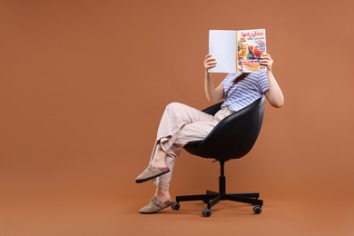 Photo of Woman with lifestyle magazine on armchair against brown background, space for text