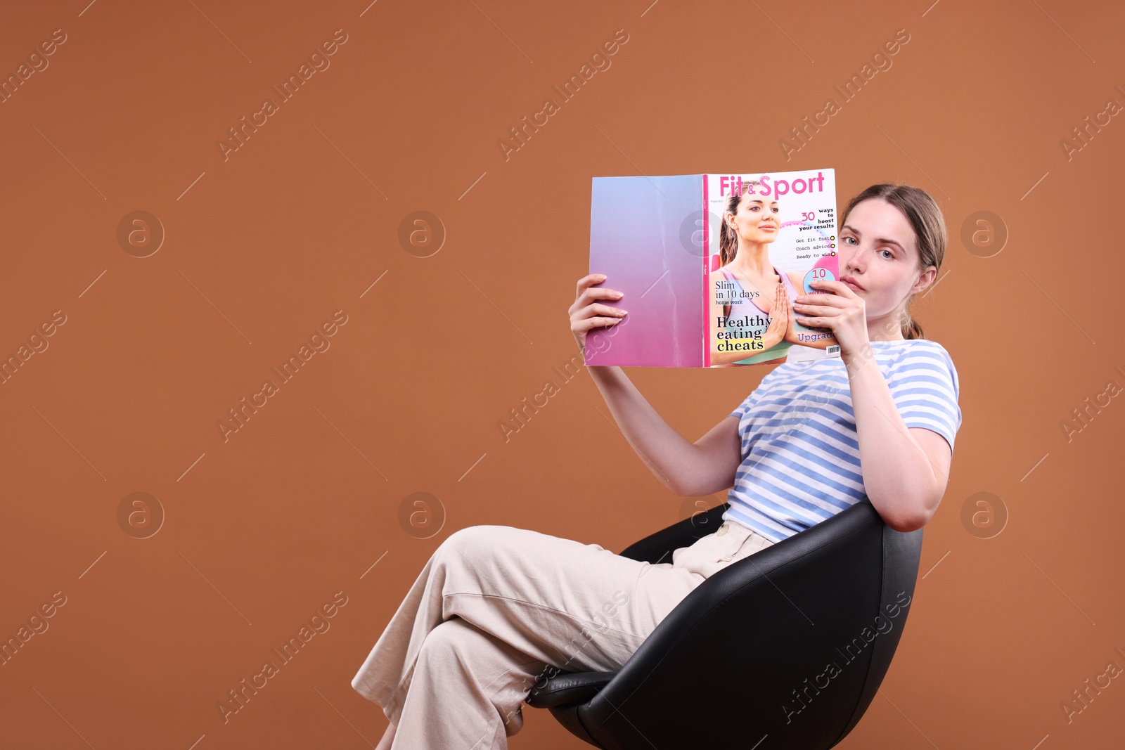 Woman with lifestyle magazine on armchair against brown background, space for text Photo of Woman with lifestyle magazine on armchair against brown background, space for text