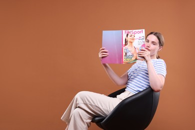 Photo of Woman with lifestyle magazine on armchair against brown background, space for text