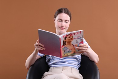 Photo of Woman with lifestyle magazine on armchair against brown background