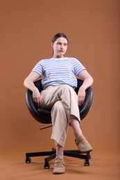 Photo of Beautiful young woman sitting on armchair against brown background