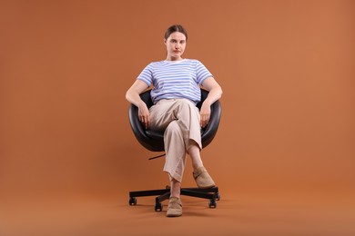 Photo of Beautiful young woman sitting on armchair against brown background