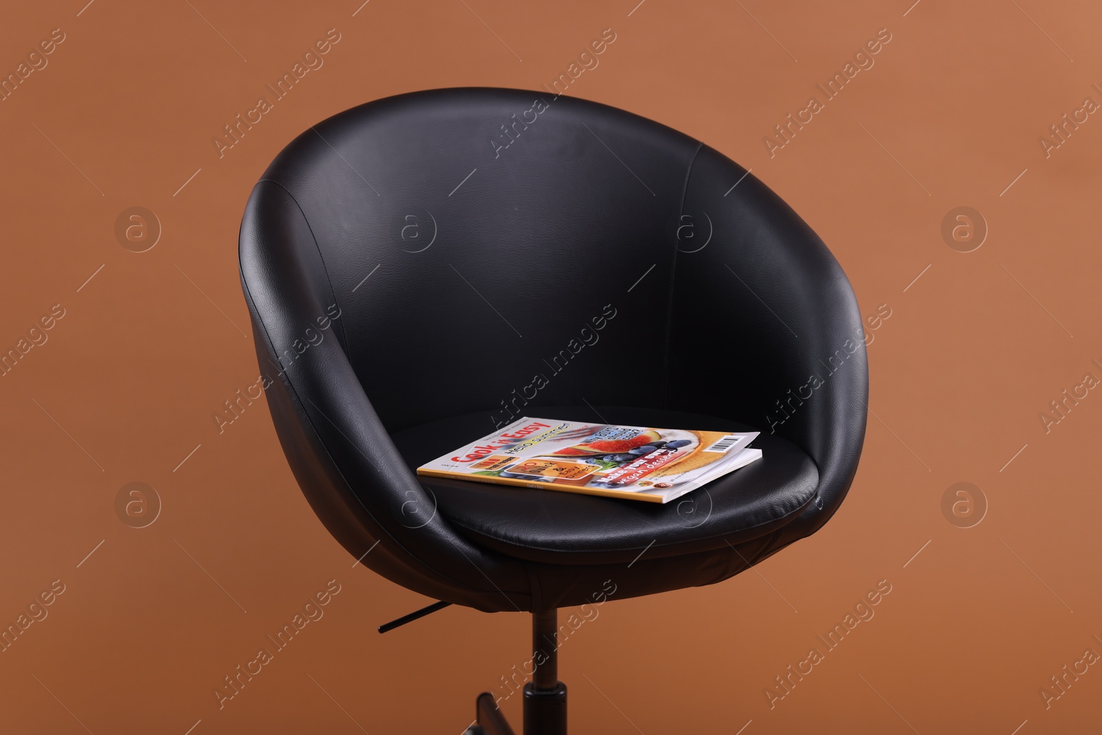 Lifestyle magazine on armchair against brown background Photo of Lifestyle magazine on armchair against brown background
