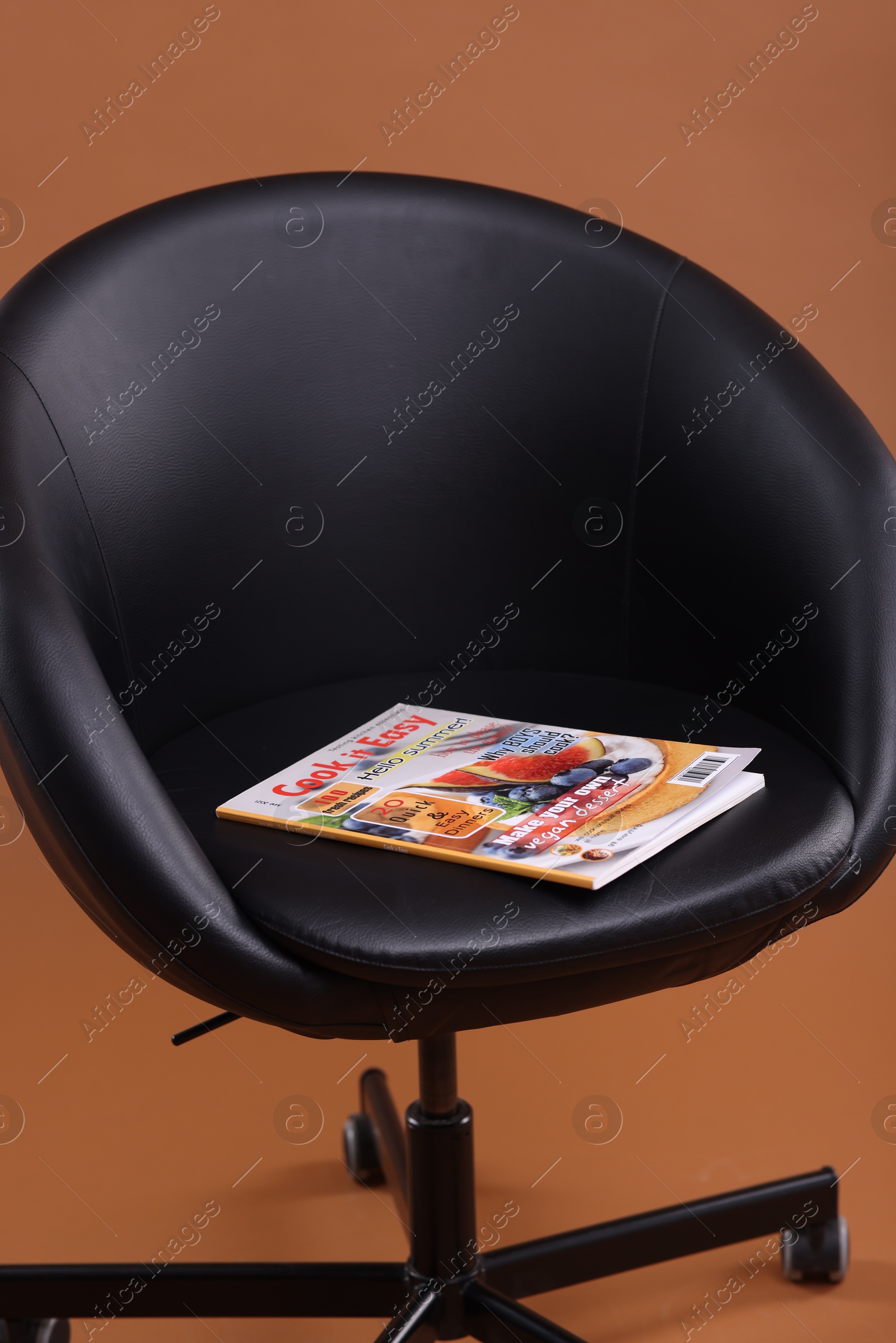 Lifestyle magazine on armchair against brown background, closeup Photo of Lifestyle magazine on armchair against brown background, closeup