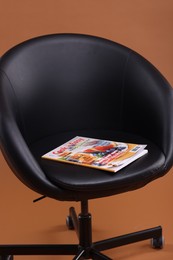 Photo of Lifestyle magazine on armchair against brown background, closeup