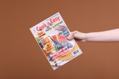 Photo of Woman with lifestyle magazine on brown background, closeup