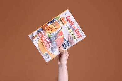 Photo of Woman with lifestyle magazine on brown background, closeup