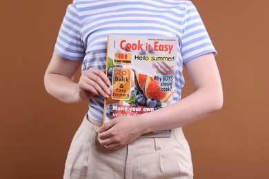 Photo of Woman with lifestyle magazine on brown background, closeup