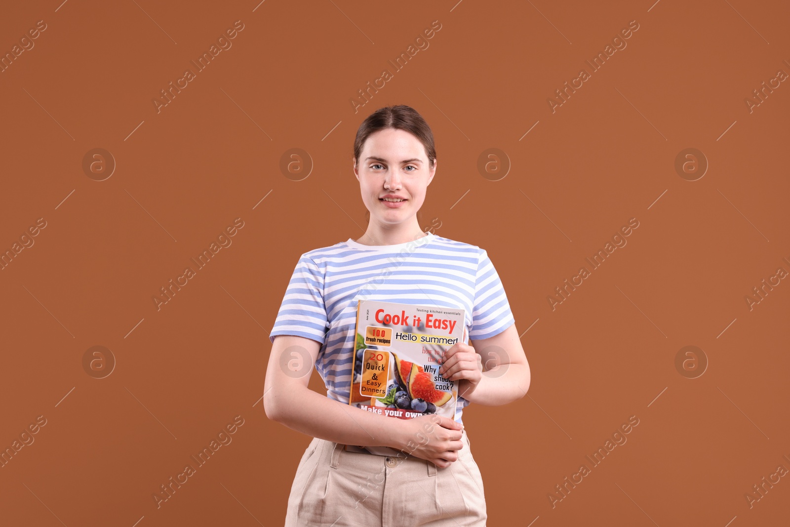 Woman with lifestyle magazine on brown background Photo of Woman with lifestyle magazine on brown background