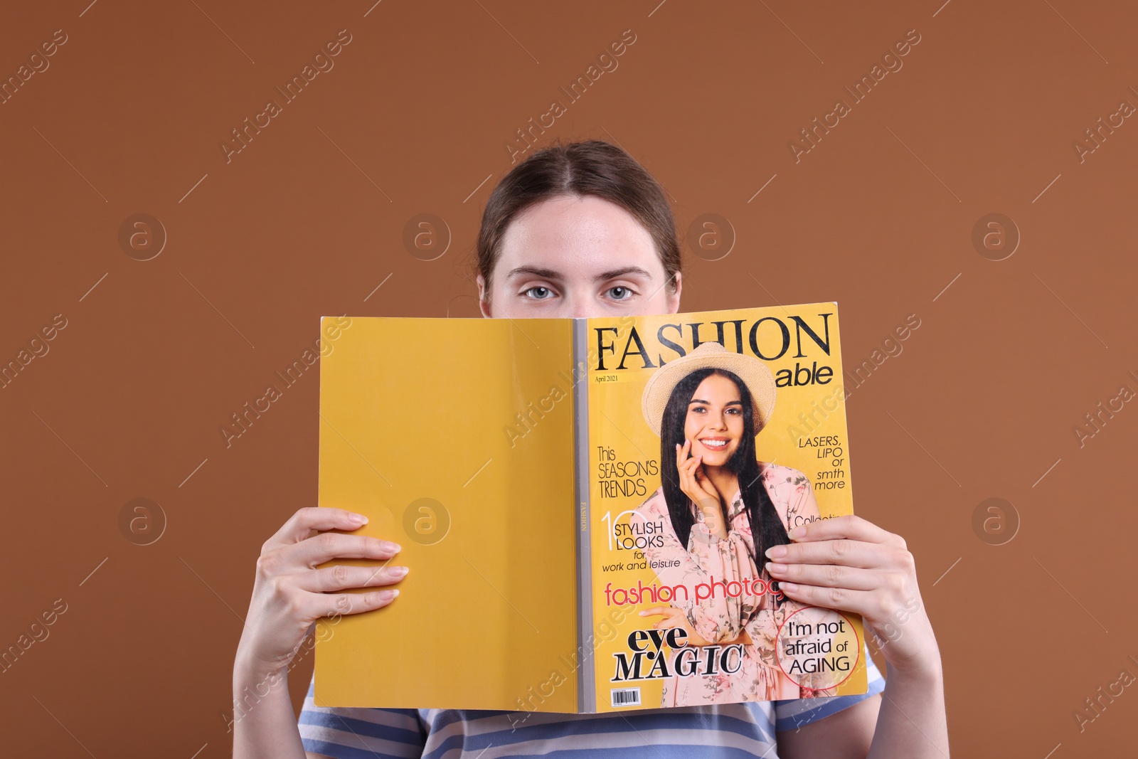 Woman with fashion magazine on brown background Photo of Woman with fashion magazine on brown background