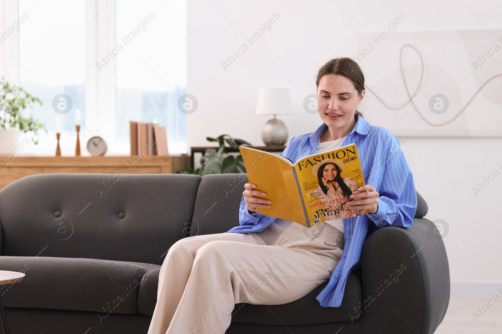 Woman reading lifestyle magazine on sofa at home Photo of Woman reading lifestyle magazine on sofa at home