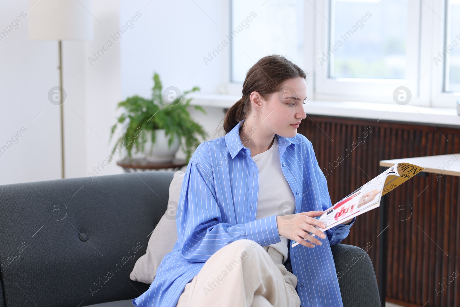 Woman reading lifestyle magazine on sofa at home Photo of Woman reading lifestyle magazine on sofa at home