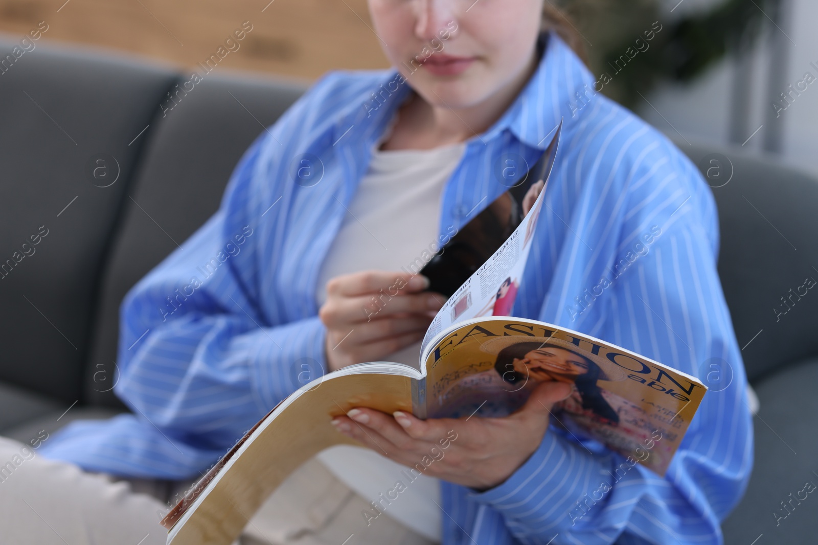 Woman reading lifestyle magazine on sofa at home, closeup Photo of Woman reading lifestyle magazine on sofa at home, closeup