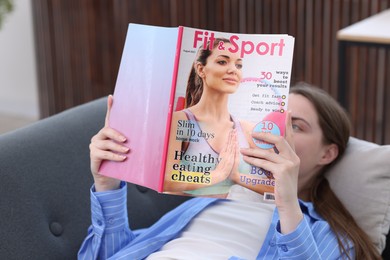 Photo of Woman reading lifestyle magazine on sofa at home