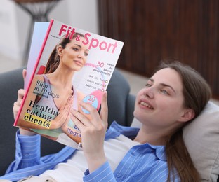 Photo of Woman reading lifestyle magazine on sofa at home, selective focus