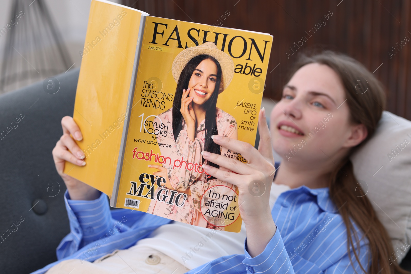 Woman reading fashion magazine on sofa at home, selective focus Photo of Woman reading fashion magazine on sofa at home, selective focus