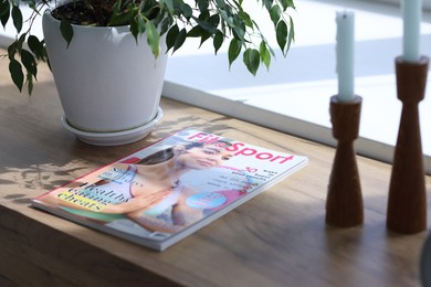 Photo of Lifestyle magazine and houseplant on wooden table indoors, closeup