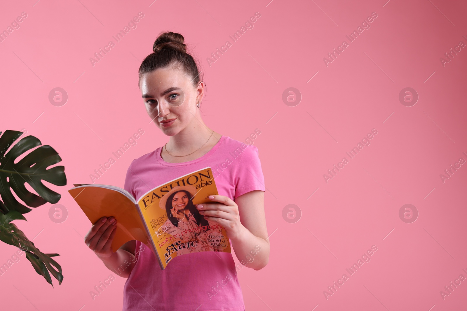 Woman with fashion magazine on pink background, space for text Photo of Woman with fashion magazine on pink background, space for text