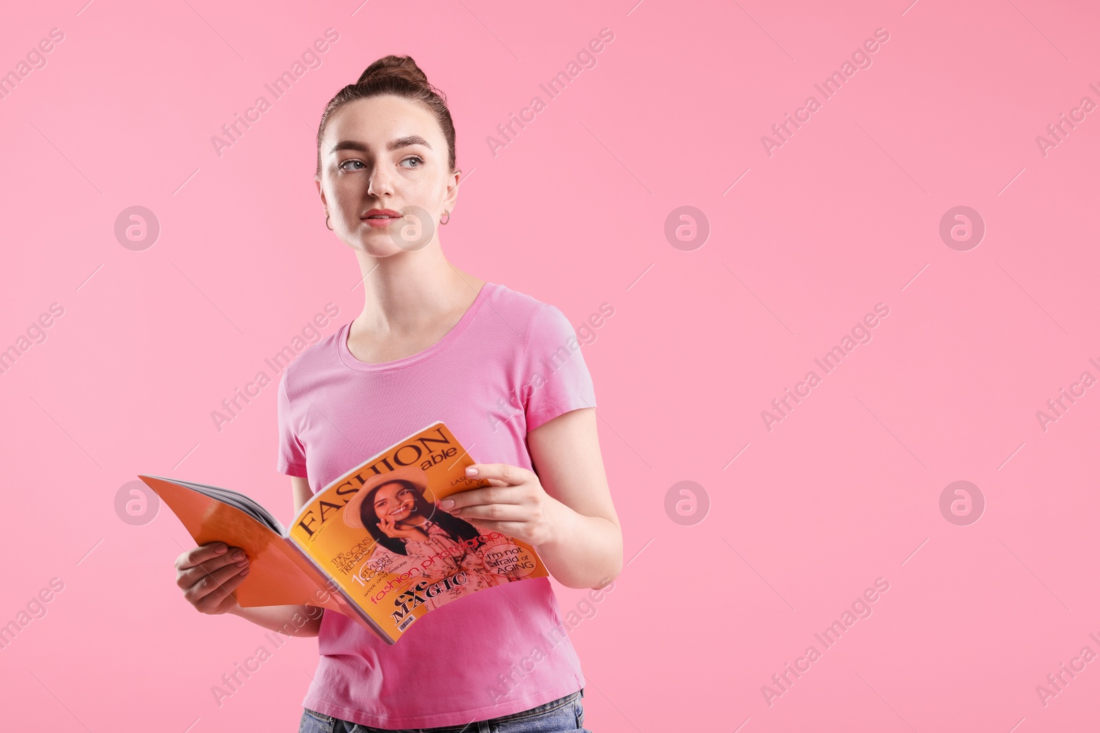 Woman with fashion magazine on pink background, space for text Photo of Woman with fashion magazine on pink background, space for text