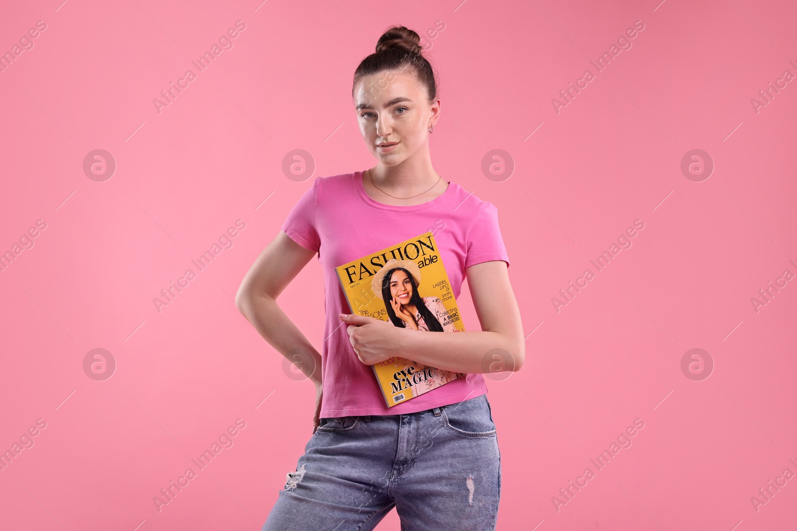 Woman with fashion magazine on pink background Photo of Woman with fashion magazine on pink background