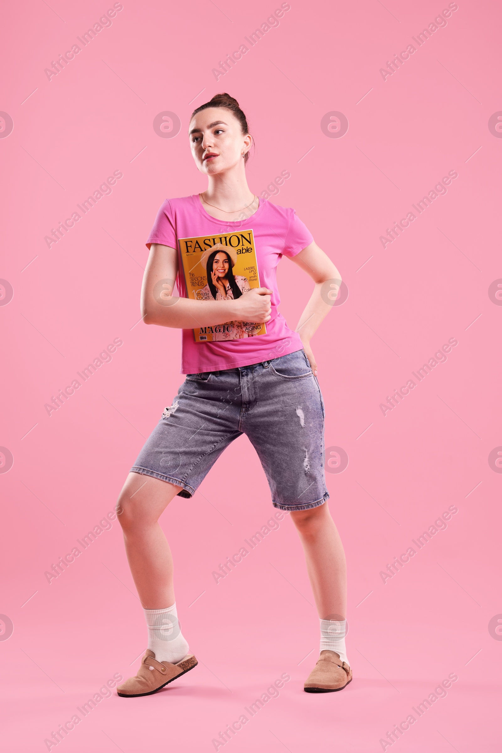 Woman with fashion magazine on pink background Photo of Woman with fashion magazine on pink background