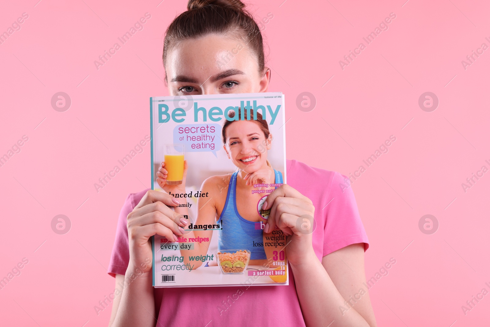 Woman with lifestyle magazine on pink background Photo of Woman with lifestyle magazine on pink background