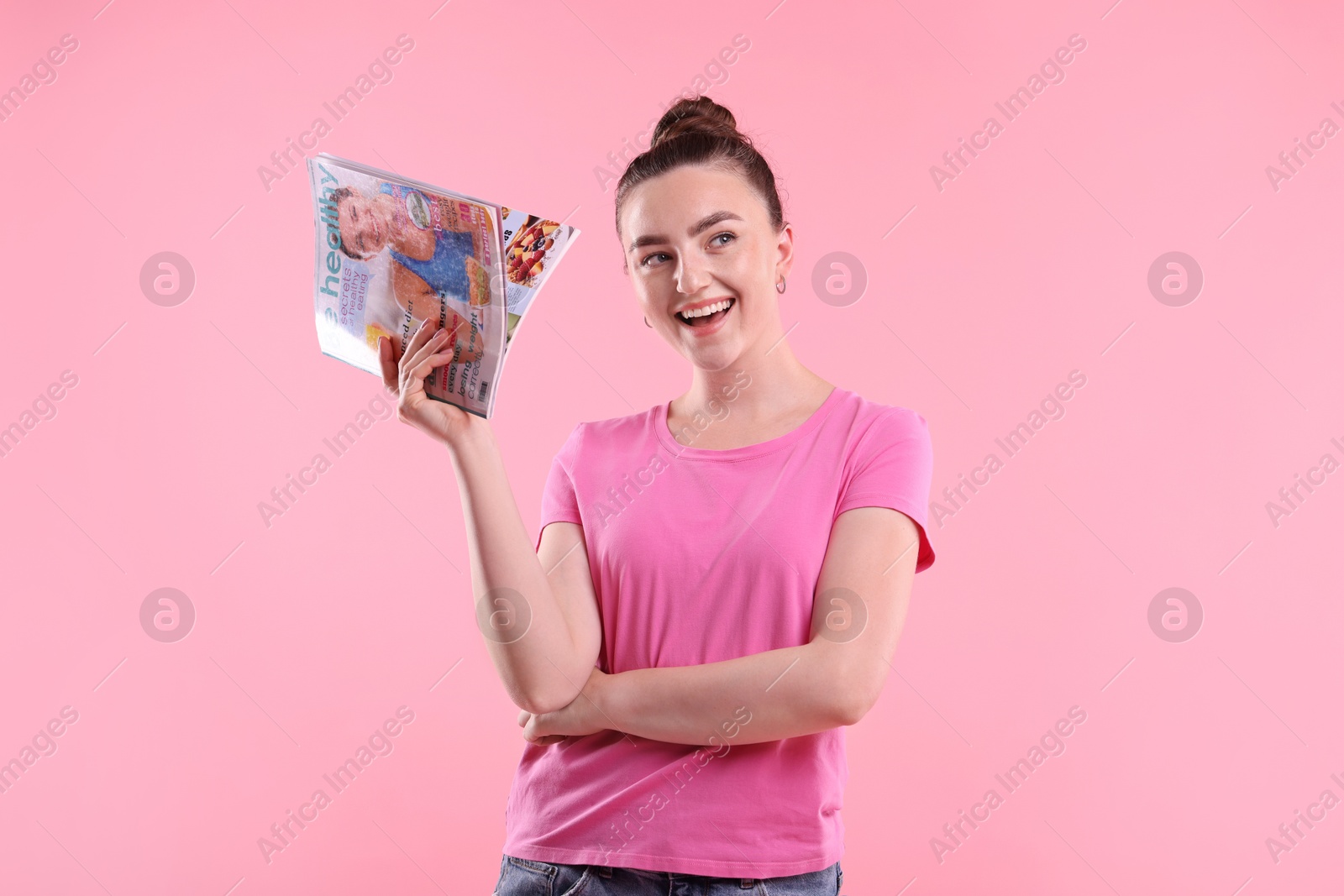 Woman with lifestyle magazine on pink background Photo of Woman with lifestyle magazine on pink background