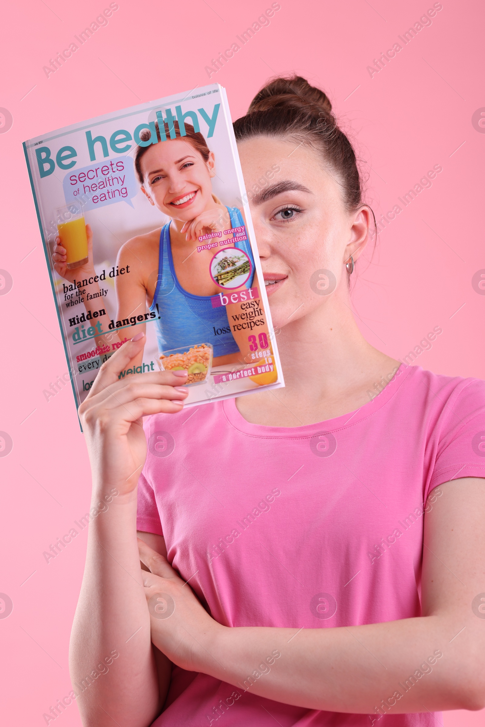 Woman with lifestyle magazine on pink background Photo of Woman with lifestyle magazine on pink background