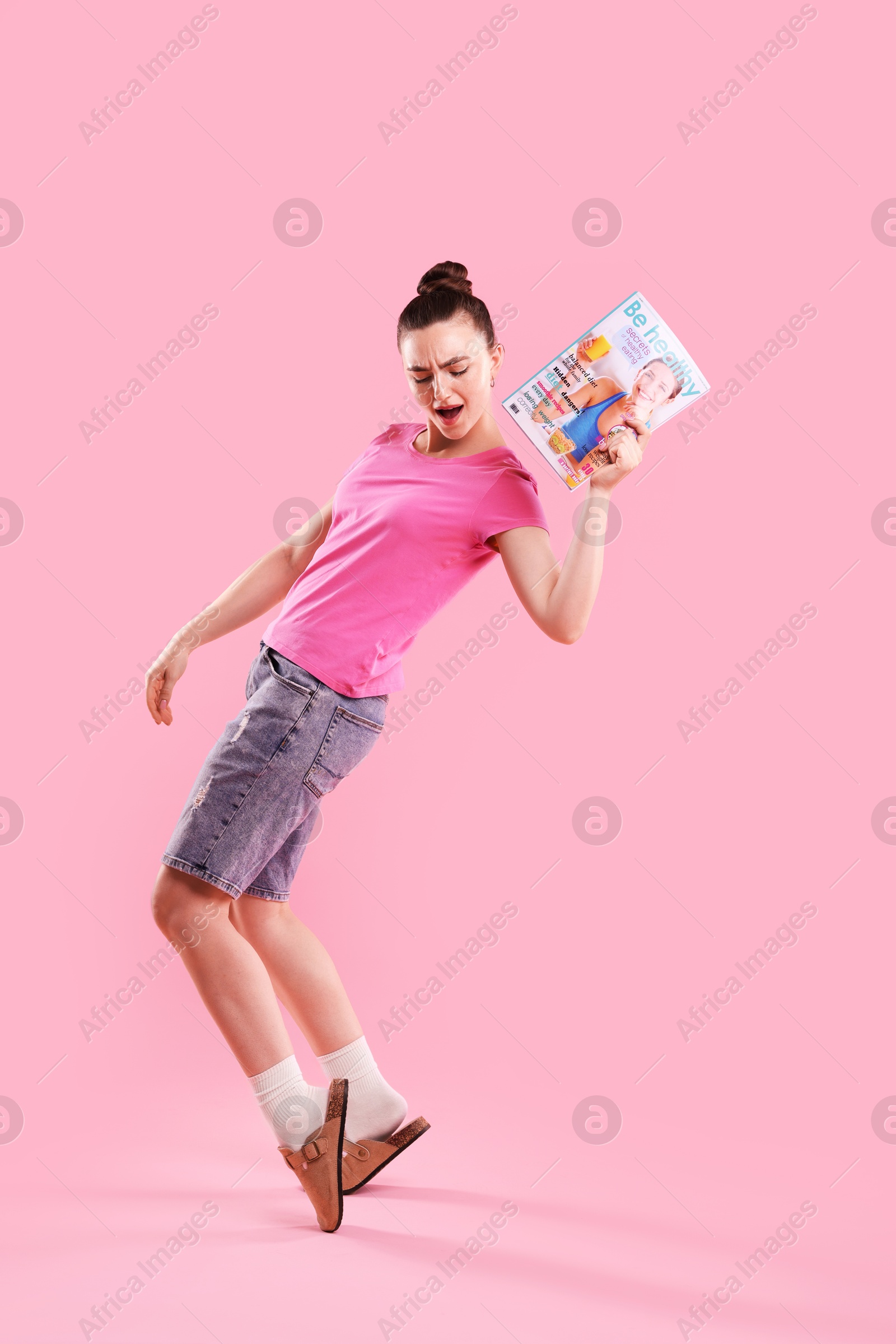 Photo of Woman with lifestyle magazine on pink background